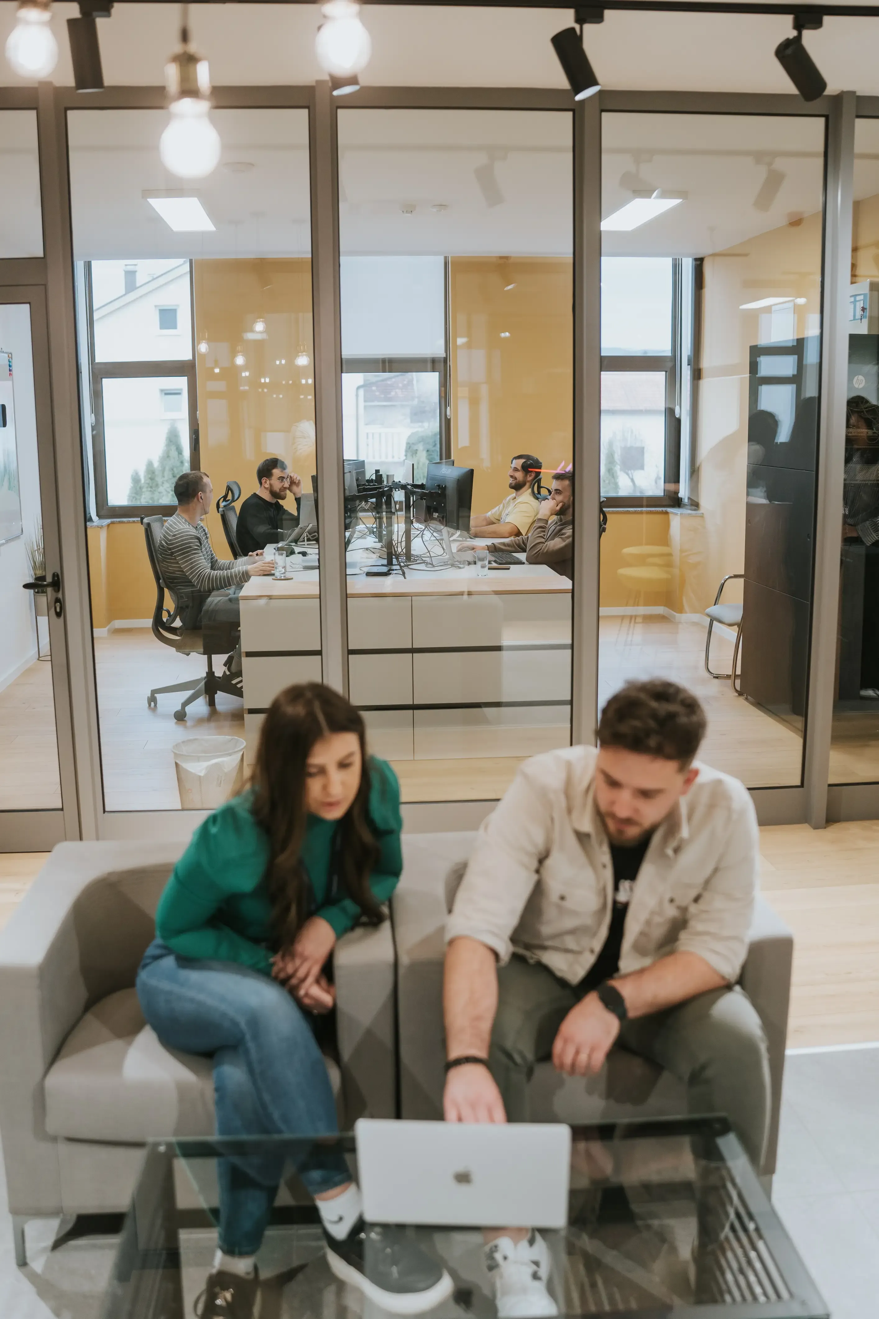 Team members discussing at laptop with other colleagues in the background